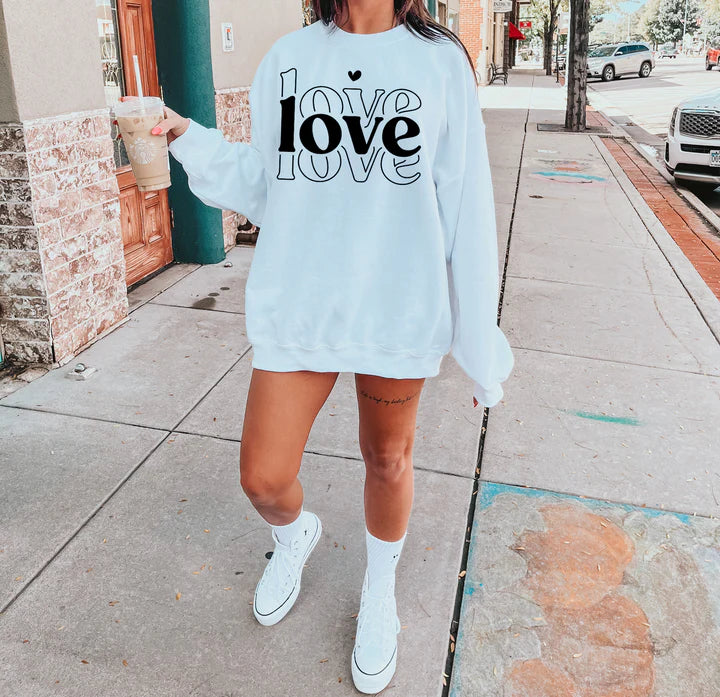 a woman wearing a love sweatshirt and shorts