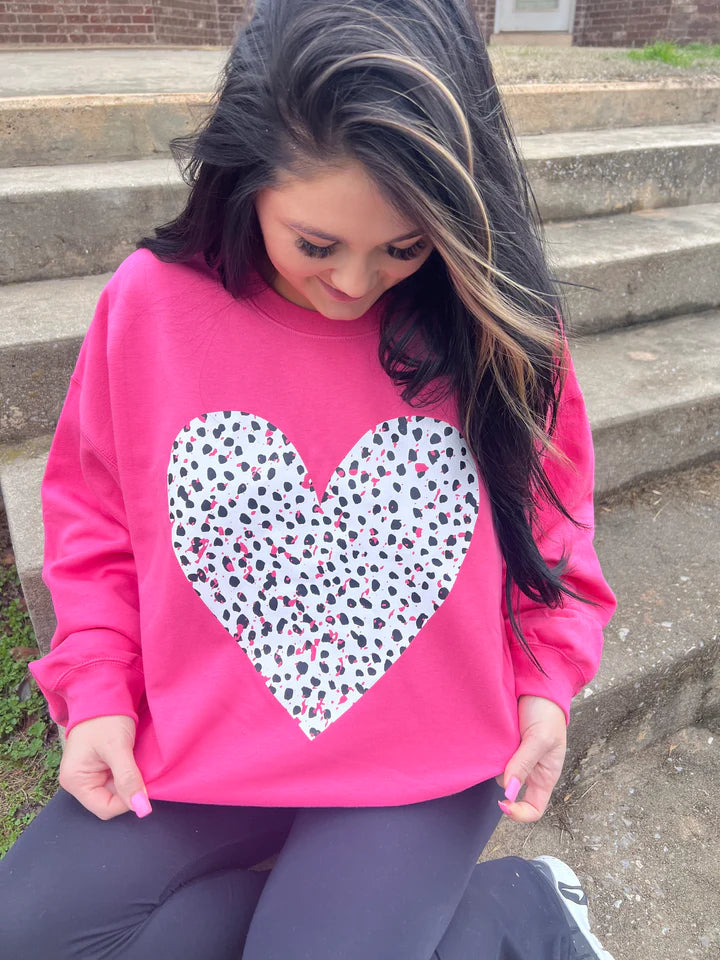 a girl sitting on the steps wearing a pink heart sweatshirt