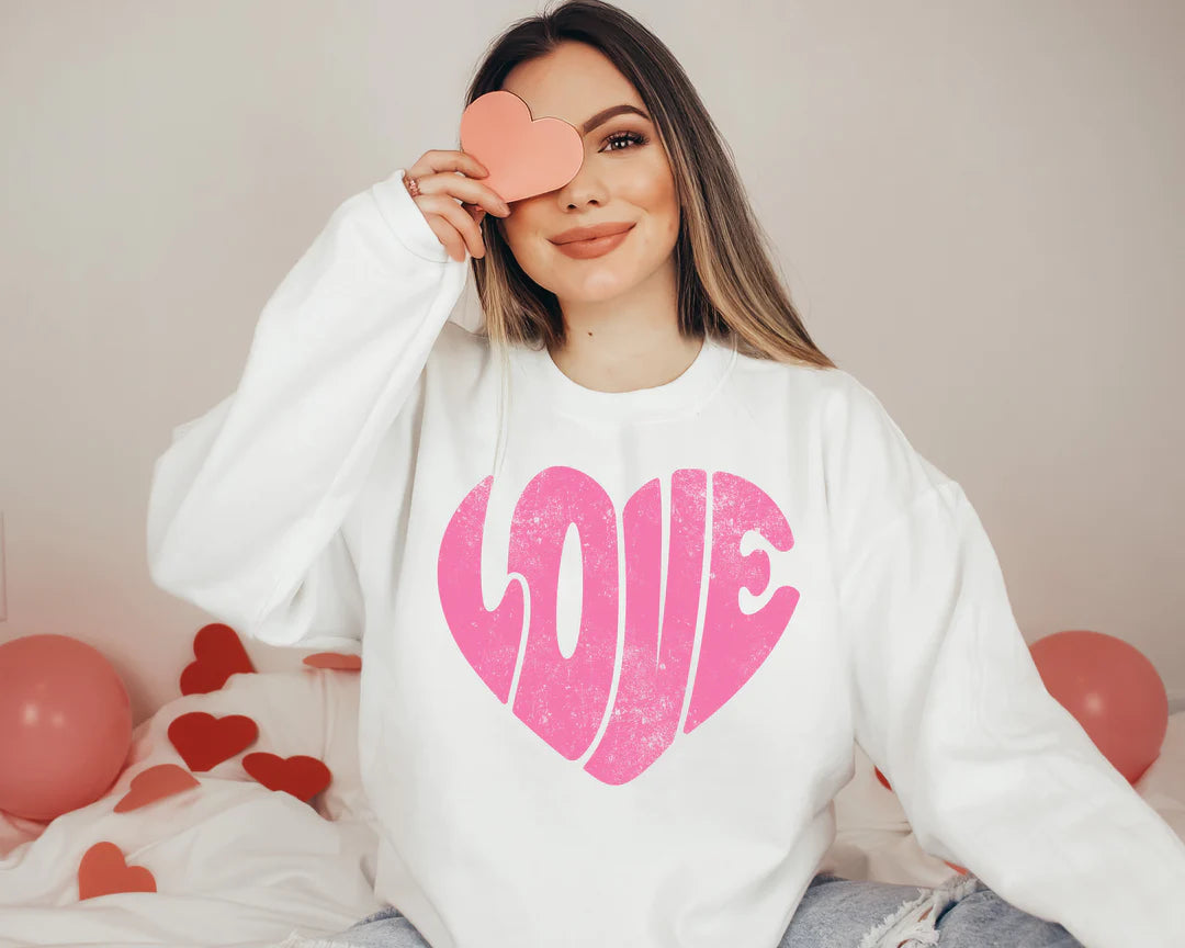 a woman sitting on a bed holding a heart shaped object