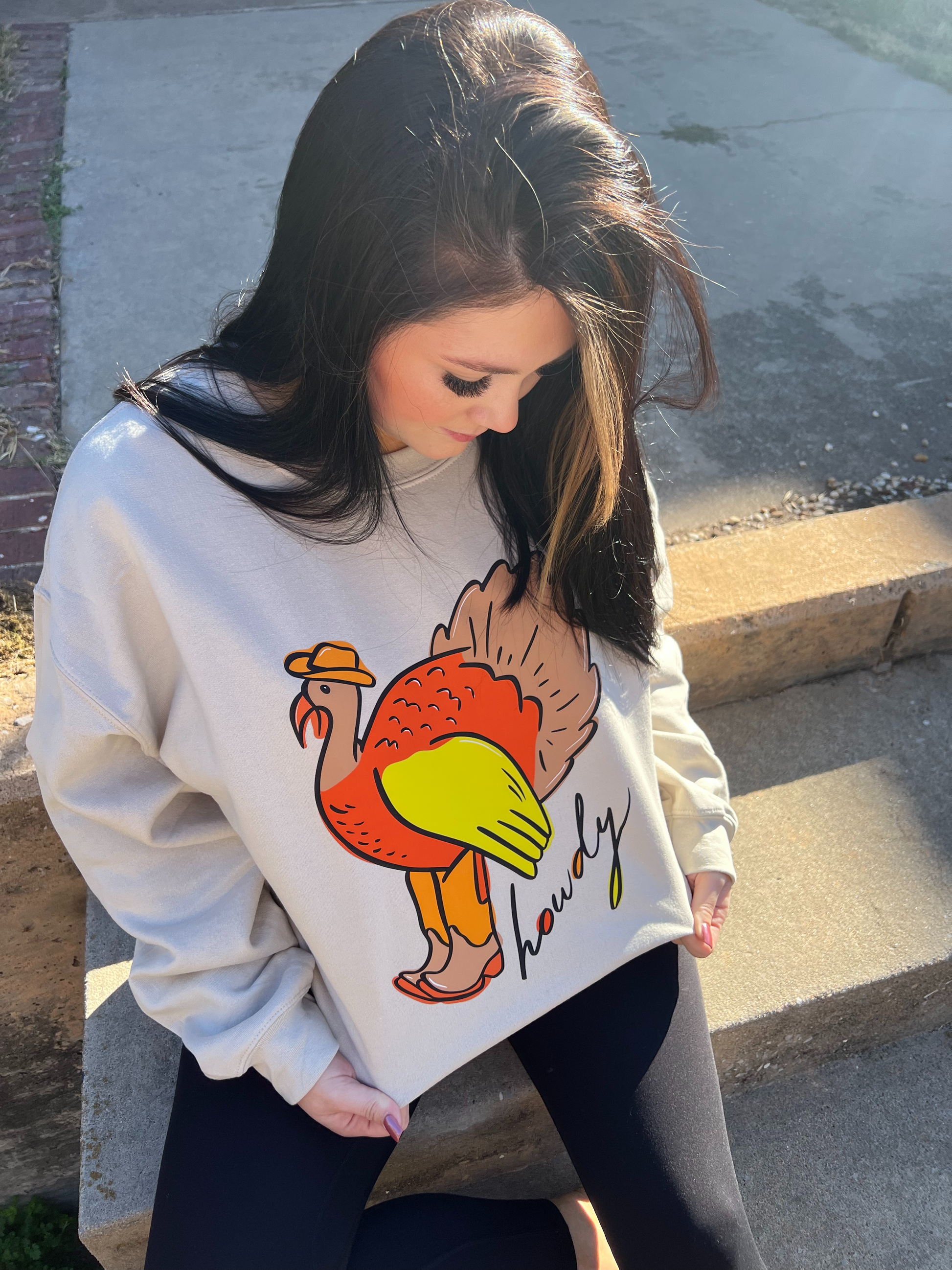 a woman sitting on the steps wearing a sweater with a turkey on it