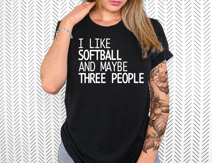 a woman wearing a black shirt that says i like softball and maybe three people