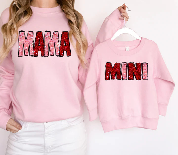 a woman wearing a pink sweatshirt with the word mama printed on it